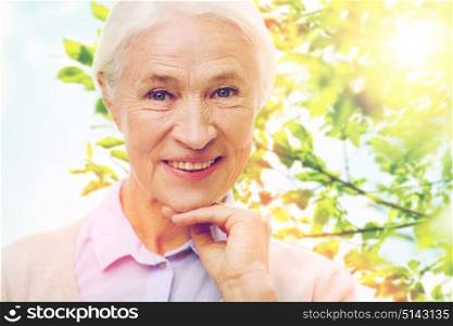 age and people concept - happy smiling senior woman face over green natural background. happy senior woman over green natural background