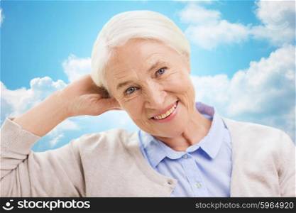 age and people concept - happy smiling senior woman over blue sky and clouds background. happy senior woman over blue sky and clouds
