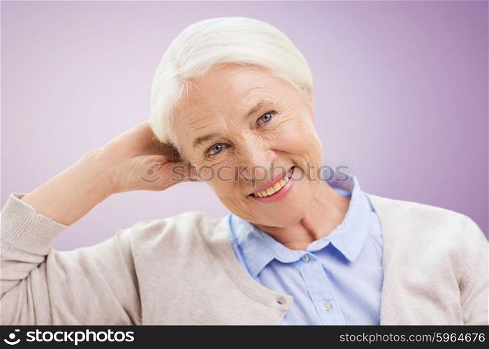 age and people concept - happy smiling senior woman over violet background. happy senior woman face over violet background