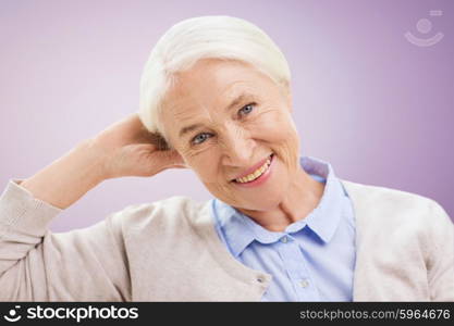 age and people concept - happy smiling senior woman over violet background. happy senior woman face over violet background
