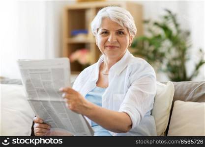 age and people concept - senior woman reading newspaper at home. senior woman reading newspaper at home