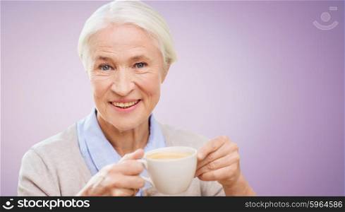 age, drink and people concept - happy smiling senior woman with cup of coffee over violet background