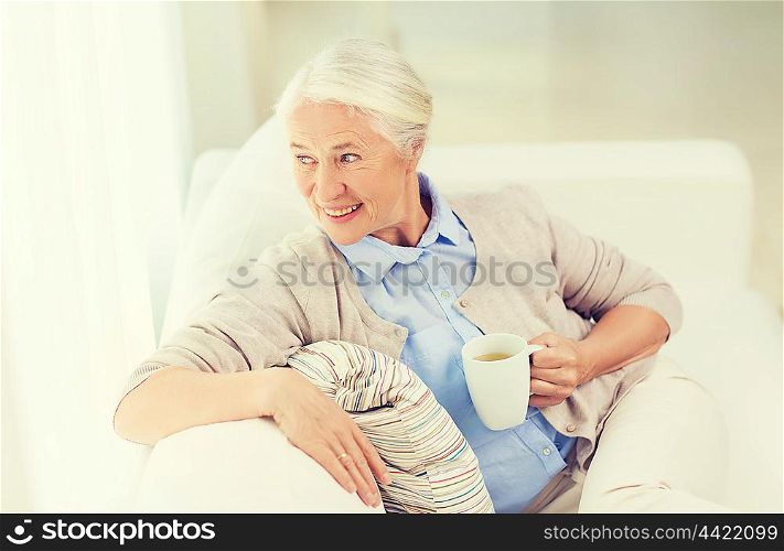 age, drink and people concept - happy smiling senior woman with cup of tea at home