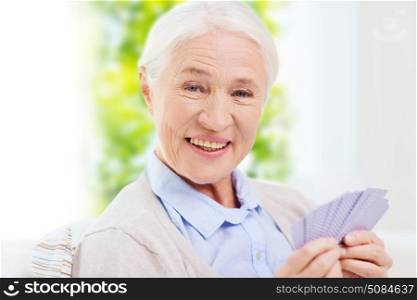 age, game, gamble, poker and people concept - happy smiling senior woman playing cards at home. happy senior woman playing cards at home. happy senior woman playing cards at home