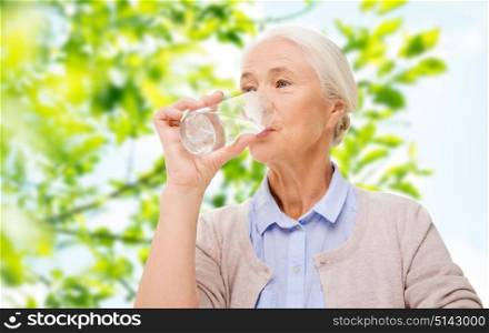age, health and people concept - happy senior woman with glass of water over green natural background. happy senior woman with glass of water at home