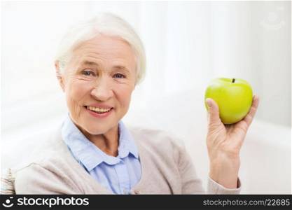 age, healthy eating, food, diet and people concept - happy smiling senior woman with green apple at home