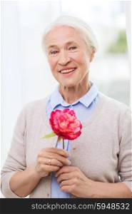 age, holidays and people concept - happy smiling senior woman with flower at home