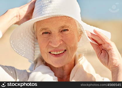 age, leisure and people concept - close up of happy senior woman in sun hat on summer beach