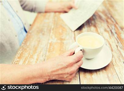 age, leisure and people concept - close up of senior woman drinking coffee and reading newspaper at home