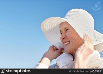 age, leisure and people concept - happy senior woman in sun hat on summer beach