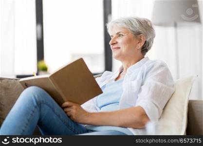 age, leisure and people concept - happy senior woman writing to notebook or diary at home. senior woman writing to notebook or diary at home