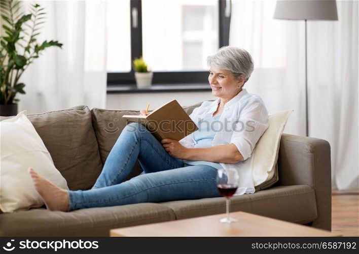 age, leisure and people concept - happy senior woman writing to notebook or diary at home. senior woman writing to notebook or diary at home