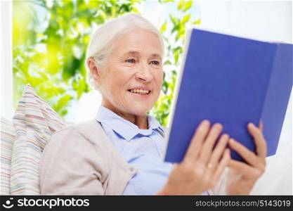 age, leisure and people concept - happy smiling senior woman reading book at home over green natural background. happy smiling senior woman reading book at home