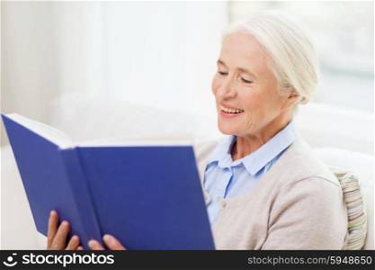 age, leisure and people concept - happy smiling senior woman reading book at home