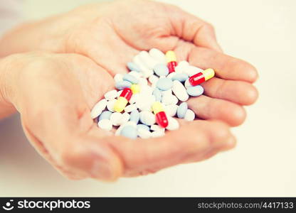 age, medicine, health care and people concept - close up of senior woman cupped hands with pills at home or hospital