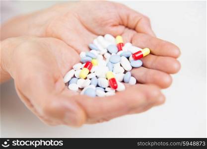 age, medicine, health care and people concept - close up of senior woman cupped hands with pills at home or hospital
