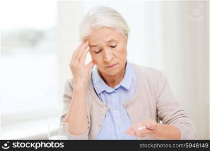 age, medicine, health care and people concept - senior woman with pills and glass of water at home