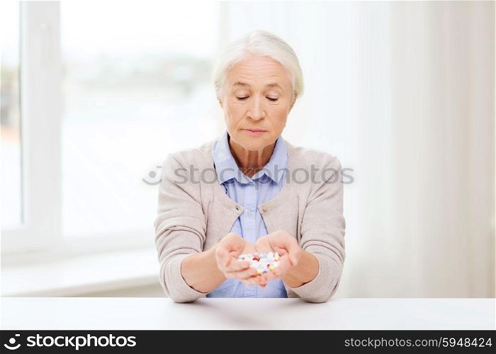 age, medicine, health care and people concept - senior woman with pills at home or hospital office