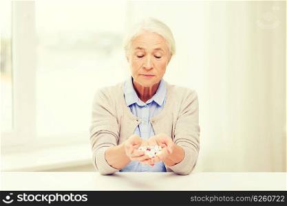 age, medicine, health care and people concept - senior woman with pills at home or hospital office