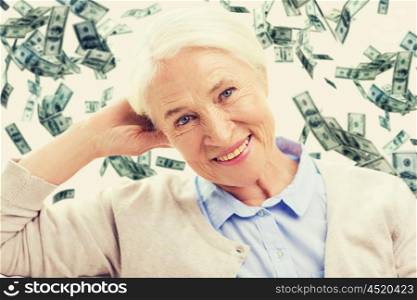 age, pension, finances, insurance and people concept - happy smiling senior woman over dollar money rain on background