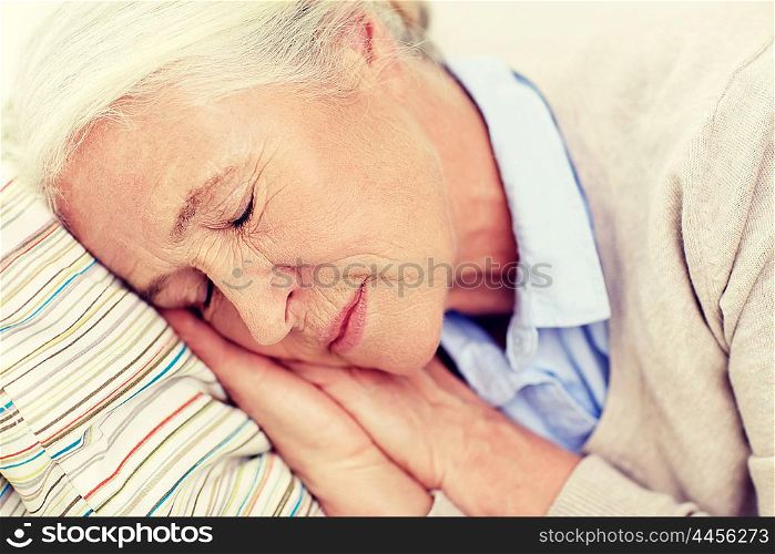 age, relax and people concept - happy senior woman sleeping on pillow at home