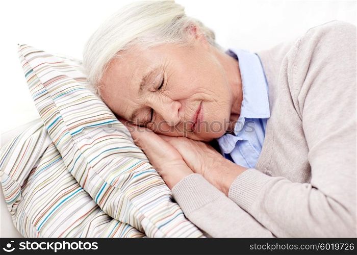age, relax and people concept - happy senior woman sleeping on pillow at home