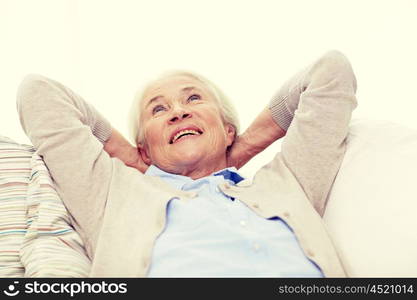 age, relax and people concept - happy smiling senior woman resting on sofa and dreaming at home