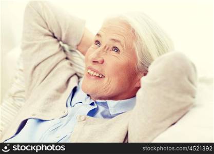age, relax and people concept - happy smiling senior woman resting on sofa and dreaming at home