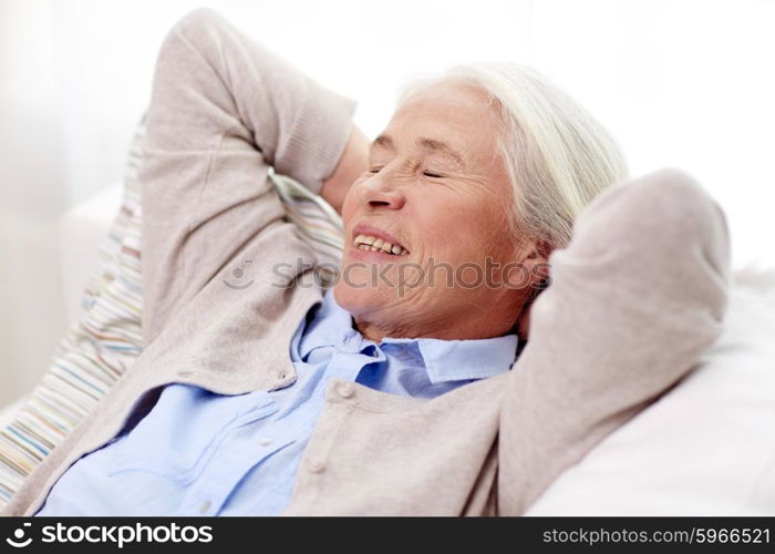 age, relax and people concept - happy smiling senior woman resting on sofa and dreaming at home