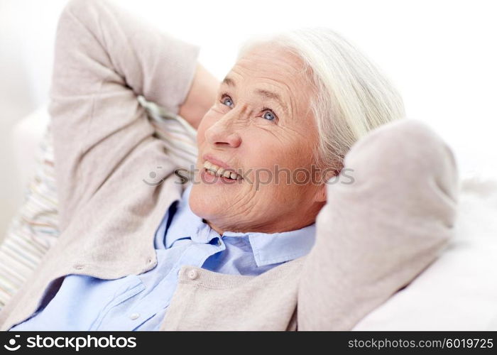 age, relax and people concept - happy smiling senior woman resting on sofa and dreaming at home