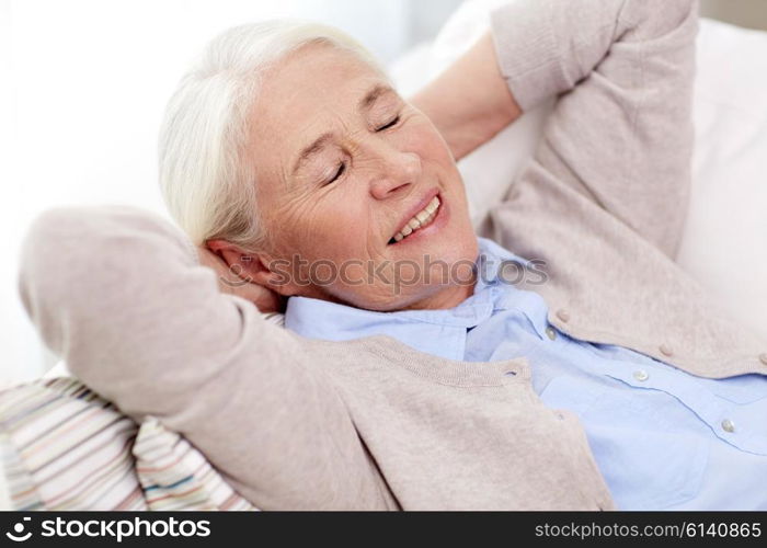 age, relax and people concept - happy smiling senior woman resting on sofa and dreaming at home