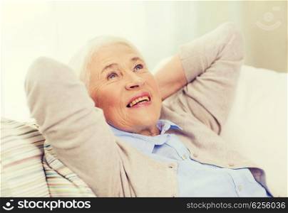 age, relax and people concept - happy smiling senior woman resting on sofa and dreaming at home