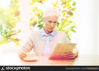 age, retirement and people concept - senior woman drinking coffee and reading newspaper over window with green natural background. senior woman with coffee reading newspaper. senior woman with coffee reading newspaper