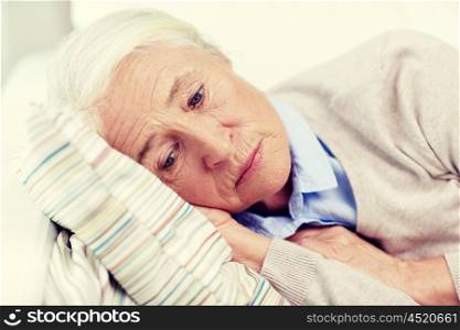 age, sadness, trouble, problem and people concept - sad senior woman sleeping on pillow at home