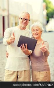 age, tourism, travel, technology and people concept - senior couple with tablet pc computer showing thumbs up gesture on street