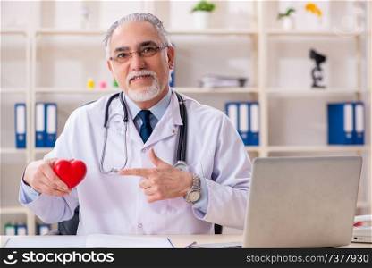 Aged male doctor cardiologist with heart model 