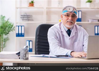 Aged male doctor laryngologist working in the clinic 