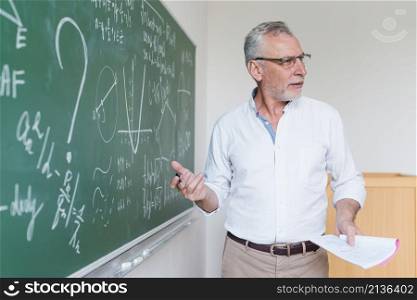 aged math teacher explaining formula classroom