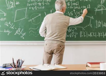 aged math teacher writing equation chalkboard