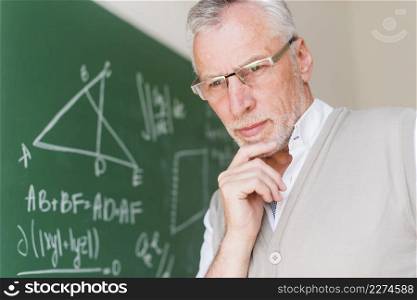 aged professor standing near chalkboard classroom