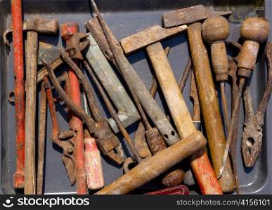 aged weathered rusty hand tools in black iron tray