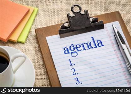 agenda list on clipboard with a pen, coffee and sticky notes against burlap canvas - office abstract