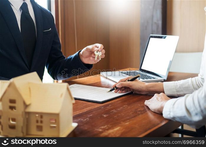 agent getting keys to customer new house, hand of real estate agent or realtor giving apartment key to receiving man after finish purchase deal agreement and sign contract, renting or buying home concept