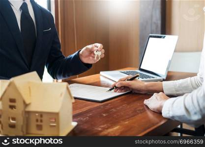 agent getting keys to customer new house, hand of real estate agent or realtor giving apartment key to receiving man after finish purchase deal agreement and sign contract, renting or buying home concept