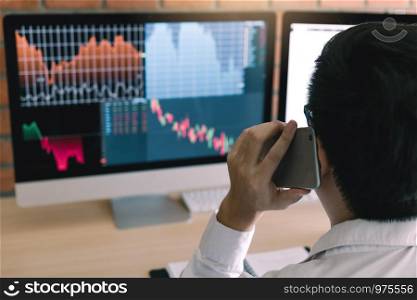 Agent trader man talking at telephone and checking business stock data on computer in office room.