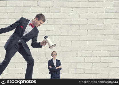 Aggression and humiliation in communication. Aggressive businessman screaming in megaphone on her colleague
