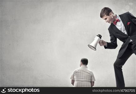 Aggression and humiliation in communication. Aggressive businessman screaming in megaphone on his colleague