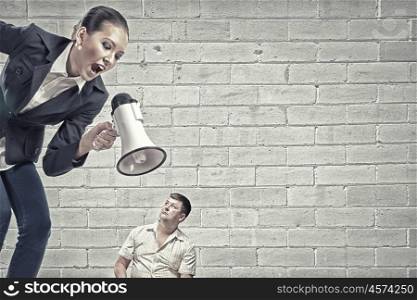 Aggression and humiliation in communication. Aggressive businesswoman screaming in megaphone on her colleague