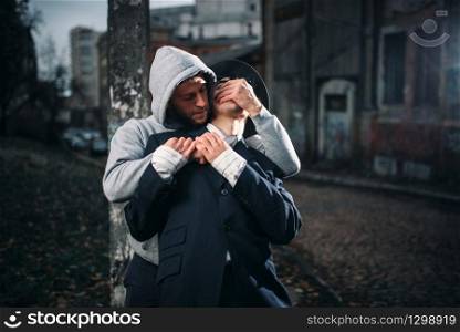 Aggressive addict with knife attack his victim on the night street. Gangster commits a robbery attack on a man. Crime concept