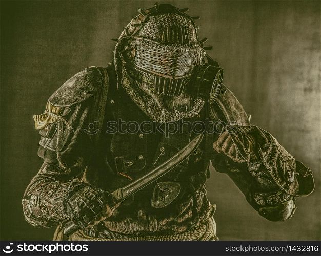 Aggressive and evil humanoid monster or creature of post apocalyptic, poisoned by dangerous pollution world wearing tattered rags and gas mask, brandishing bloodstained machete studio shoot on white. Post apocalyptic human threatening with cane knife